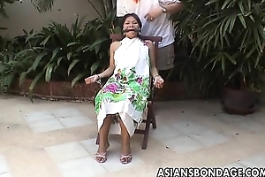 Asian teen tied up and disburse cuffed on a stool